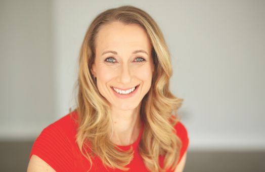 Jo Prance smiling to camera in vibrant red t-shirt